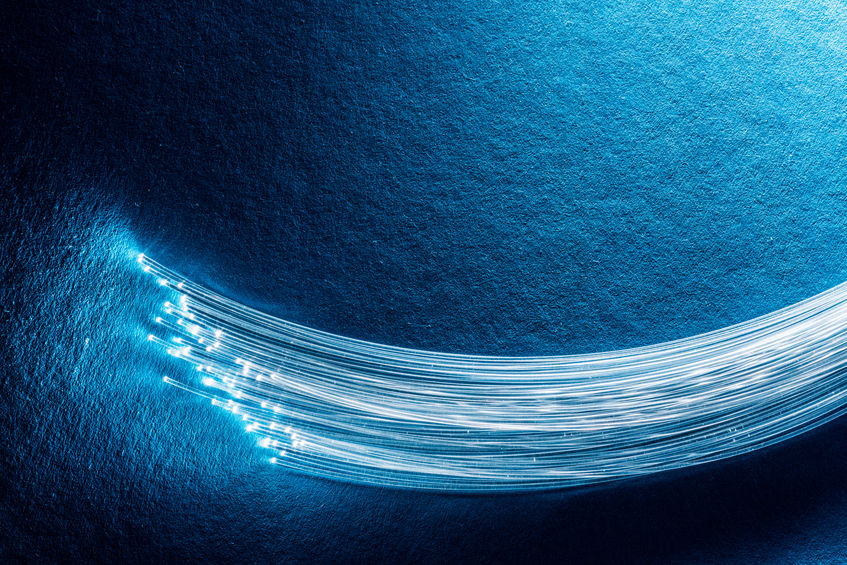 Bundle of fiber optics in front of a blue background